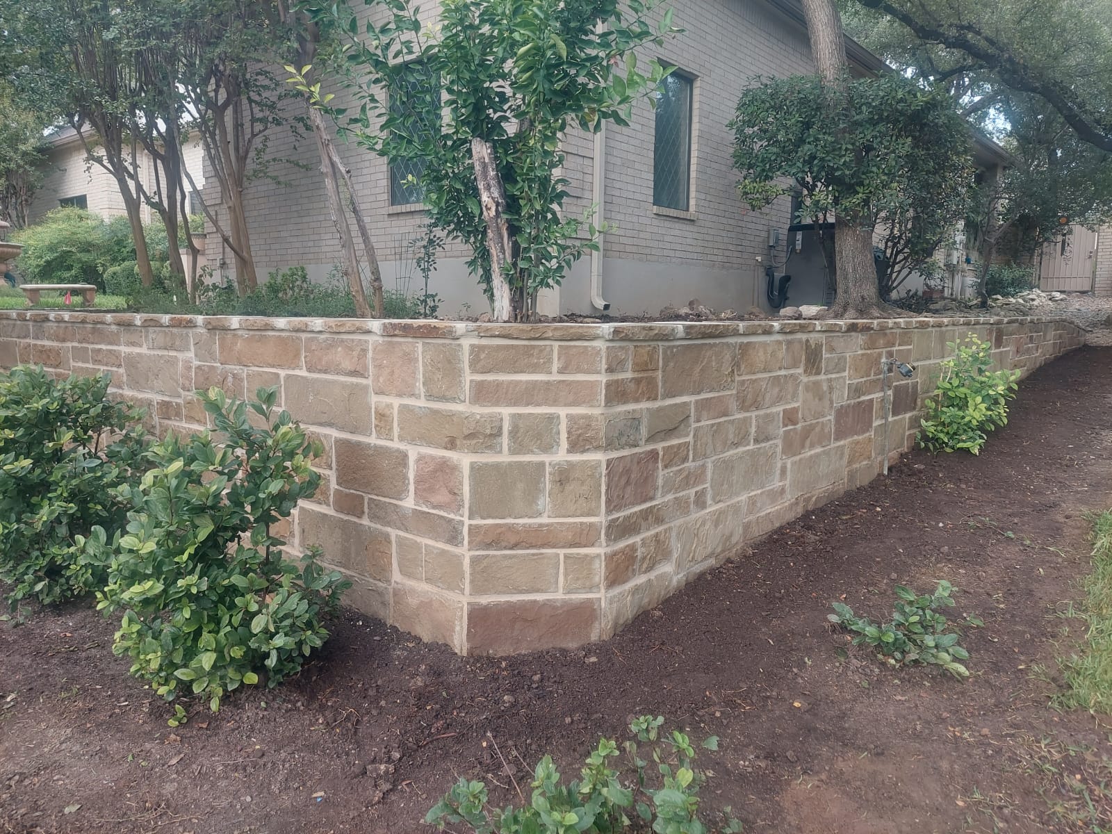 Finished stone retaining wall in a landscaped residential bed