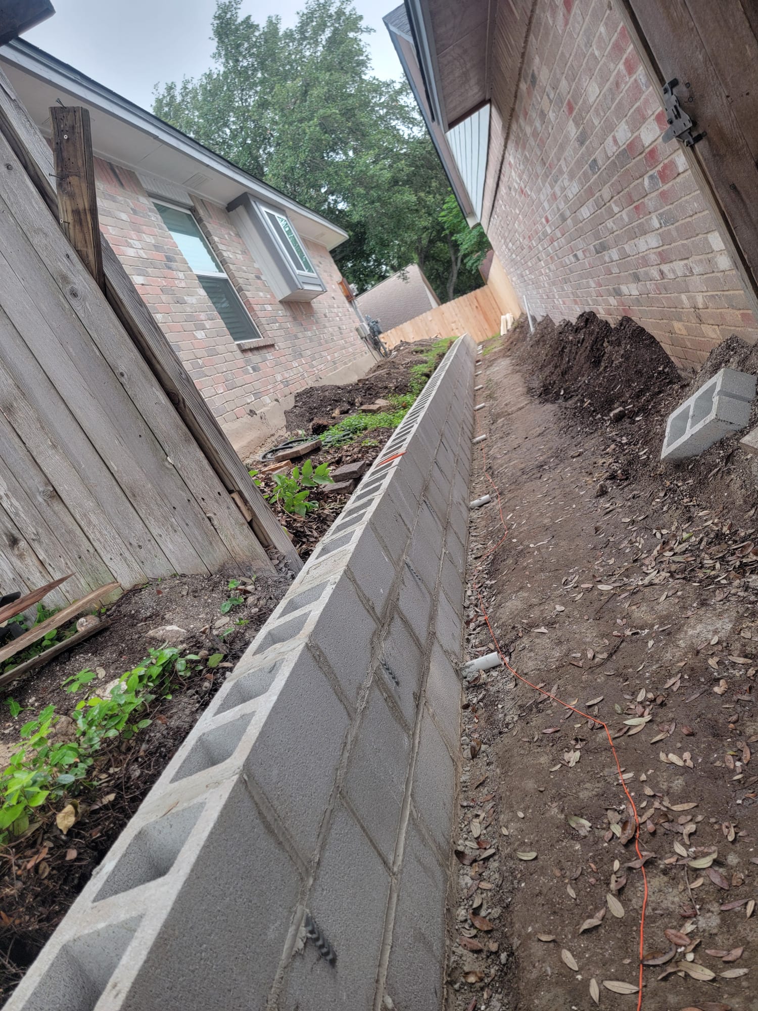 Concrete block retaining wall under construction between homes